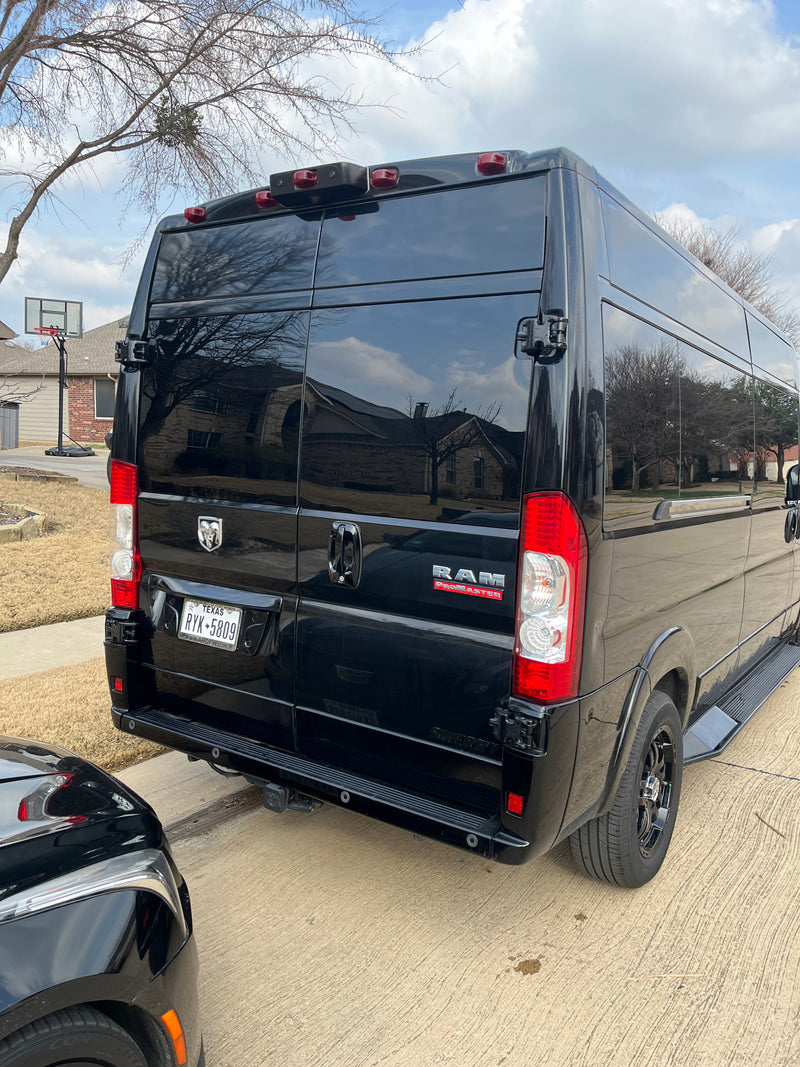 Rear view of a black Ram ProMaster RV rental van with Texas plates, parked in front of a house on a sunny day. — photo 11