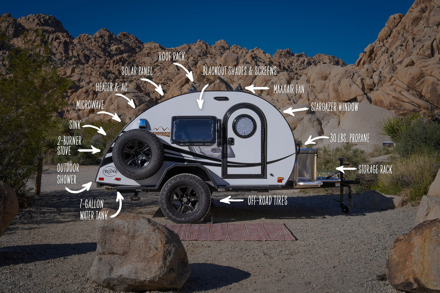 This RV rental teardrop trailer in a rocky desert landscape details its many amenities, from solar panels to an outdoor shower.