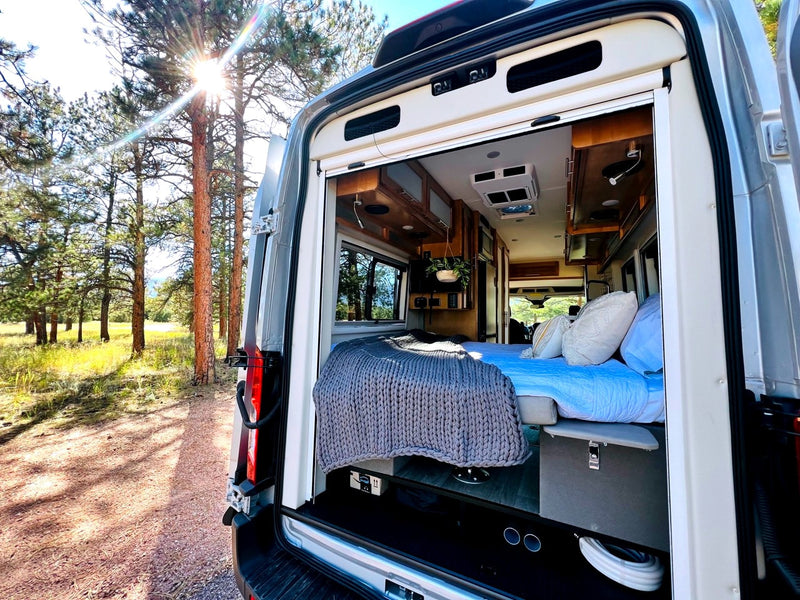Relaxing RV rental adventure! Cozy campervan interior opens to nature, sun shining through pine trees. — photo 4