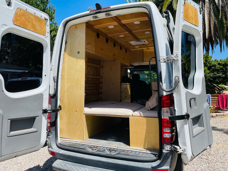 Custom wood interior of a camper van, ideal for rv rental or adventure. Features bed, storage, and cozy setup. — photo 4