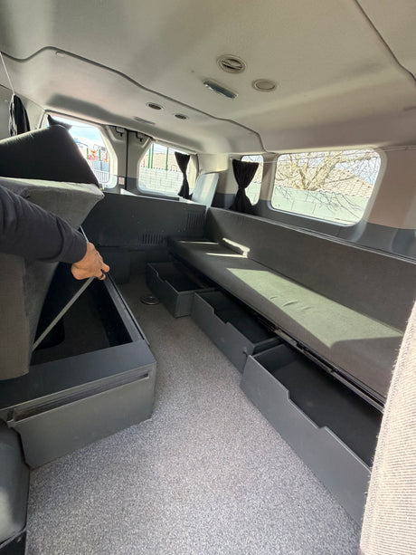 RV rental interior featuring flexible seating/bed, pull-out storage drawers, and hidden under-cushion compartments.