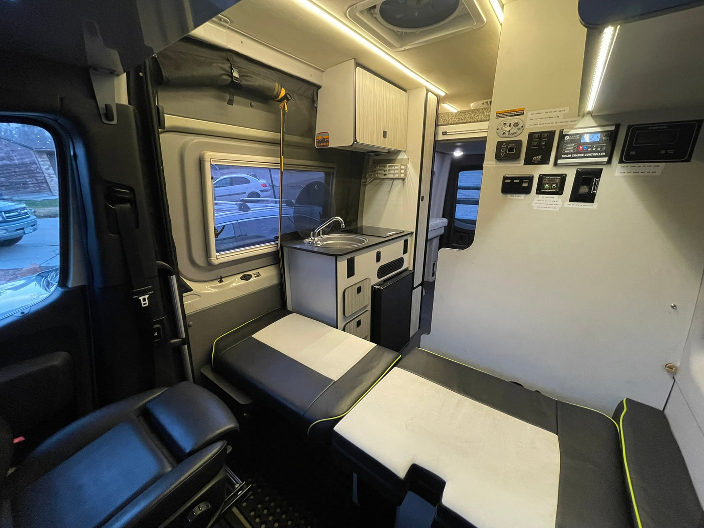 Explore the cozy interior of this RV rental, showcasing a compact kitchen, modular seating, and a clear control panel for amenities.