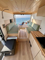 Cozy RV rental with ocean view, perfect for remote work or relaxation. Features dinette, kitchen, and comfy seating.