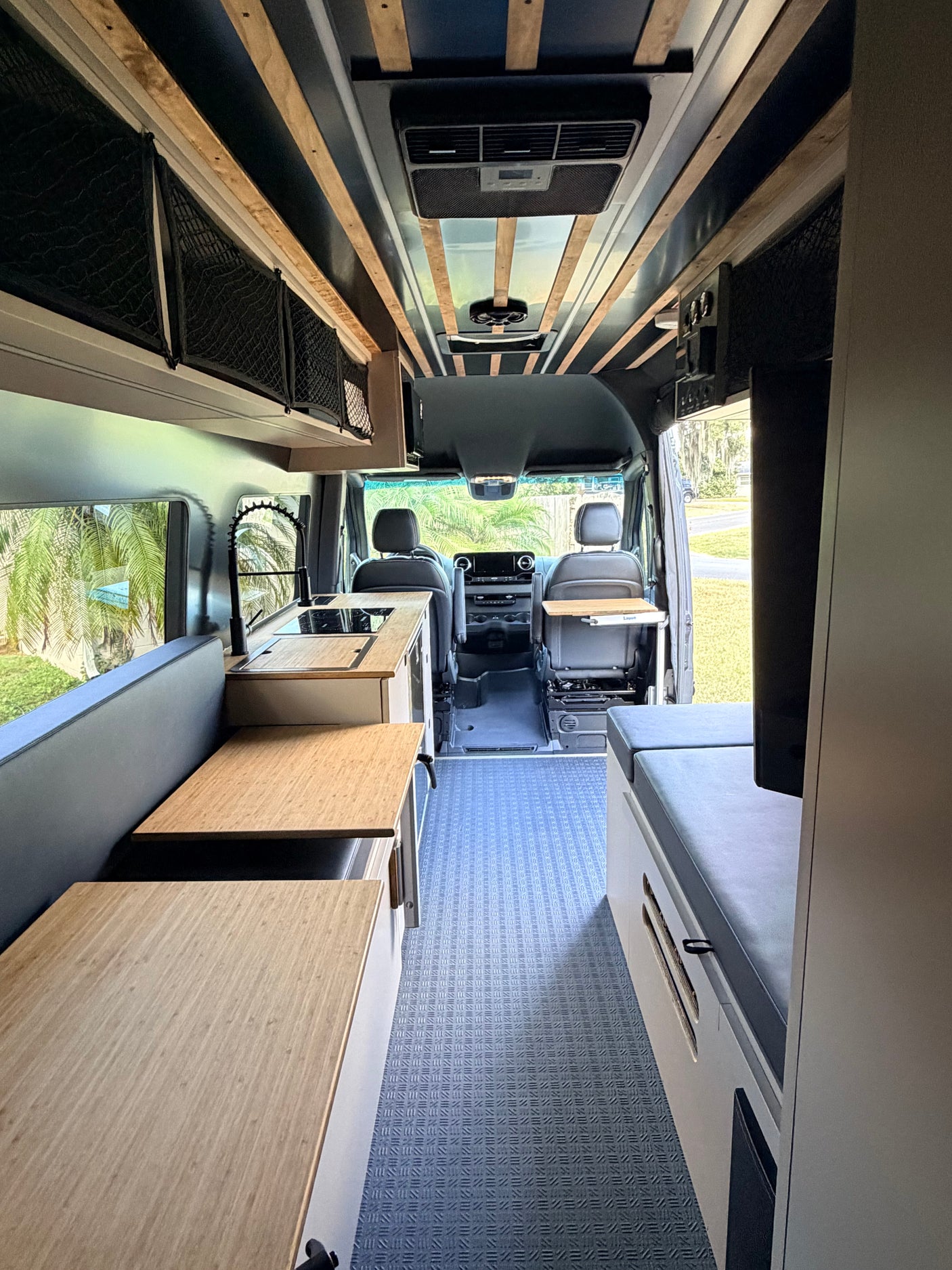 Step inside this cozy rv rental: a modern camper van featuring a kitchen, seating, storage, and a comfy bed area.