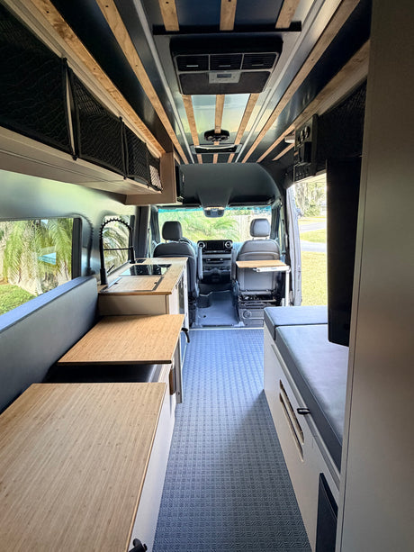 Step inside this cozy rv rental: a modern camper van featuring a kitchen, seating, storage, and a comfy bed area.