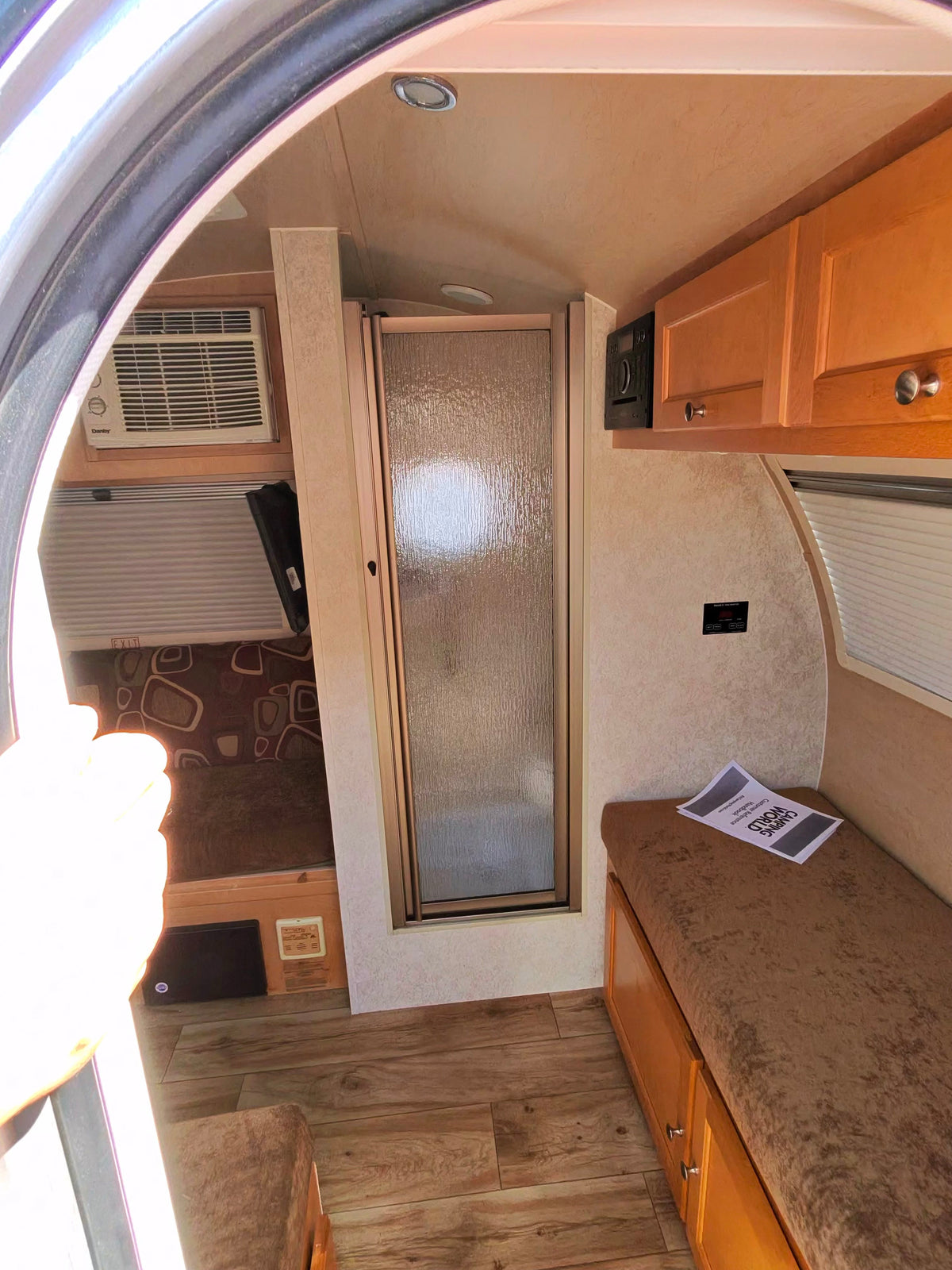 Step inside this rv rental: featuring a compact shower, comfy dinette/bed, wood-look floor, and convenient storage cabinets. — photo 6
