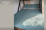 Inside our RV rental: A comfy bed with a quilted teal bedspread, pillows, and AC for your trip.
