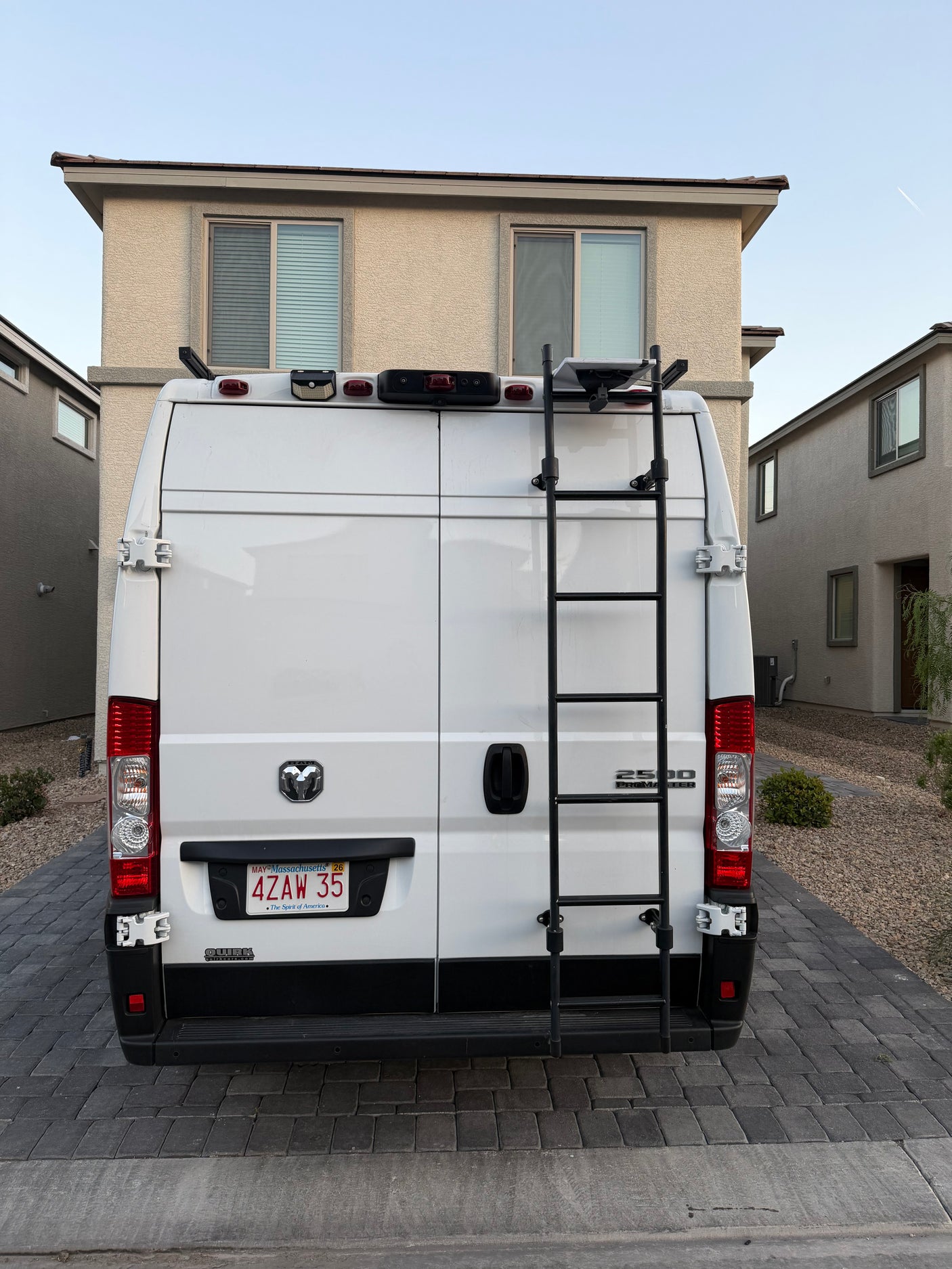 White Ram ProMaster 2500 rv rental van with a ladder & MA license plate (4ZAW 35), parked in a residential driveway.