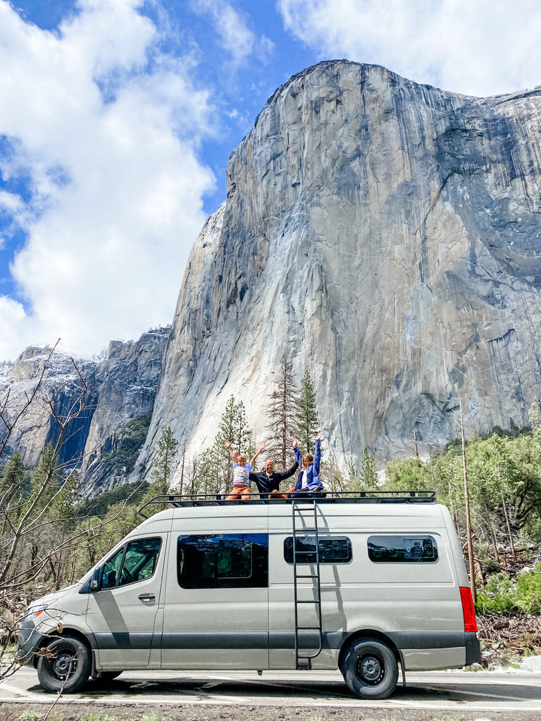 Family waves from their **RV rental** van's roof with El Capitan towering above in Yosemite.