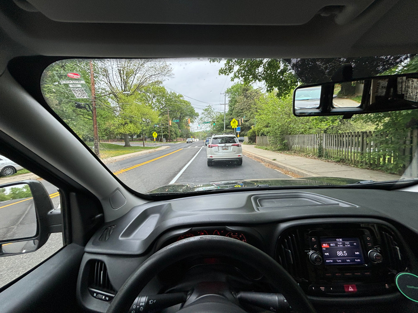 View from a car's driver seat on a tree-lined road. For road trips, an RV rental provides spacious travel options.