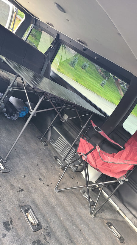Interior view of an RV rental: A portable folding table and red chair are set up inside, ready for comfortable travel.