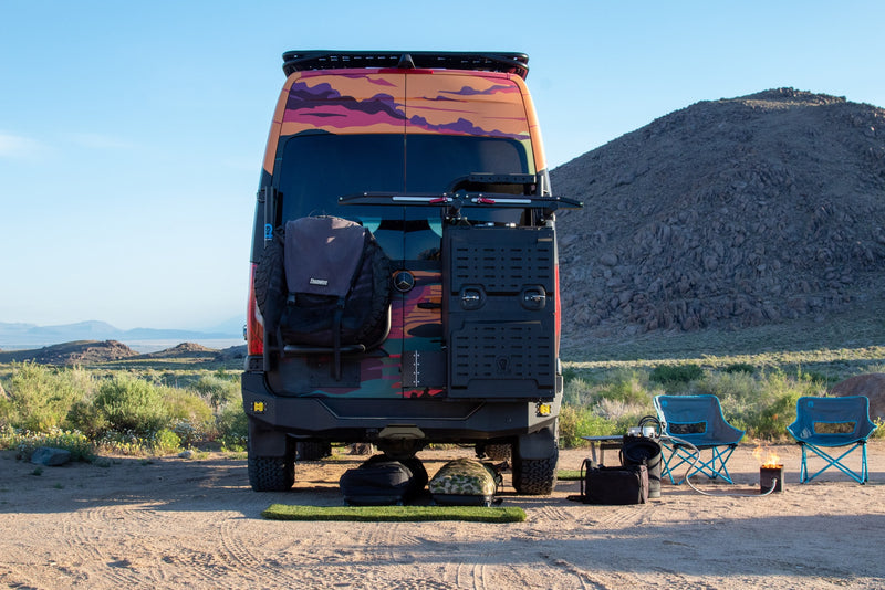  with chairs and a cozy fire pit behind the colorful van.|Colorful custom RV rental parked for camping with mountain views — photo 8