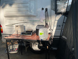 Outdoor cooking setup at an RV rental: air fryer, induction cooktop, ice maker, and water jugs. A Joolca tent is nearby.