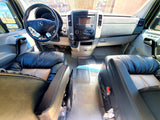 RV rental interior: A well-appointed cockpit with Mercedes steering wheel, modern dashboard, and plush black & tan leather seats.