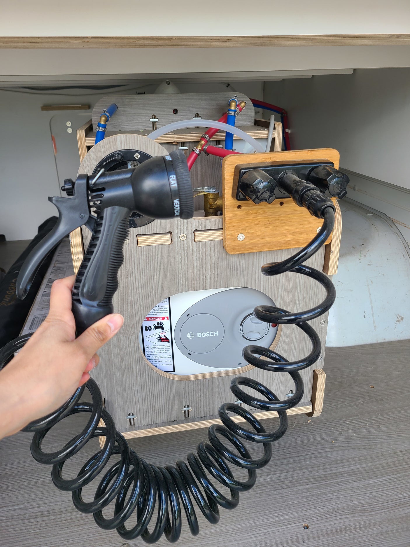 RV rental outdoor shower setup with Bosch water heater and coiled hose. Perfect for campervan adventures.