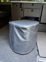Grey faux leather ottoman in an RV rental, surrounded by custom dark wood cabinetry and carpet.