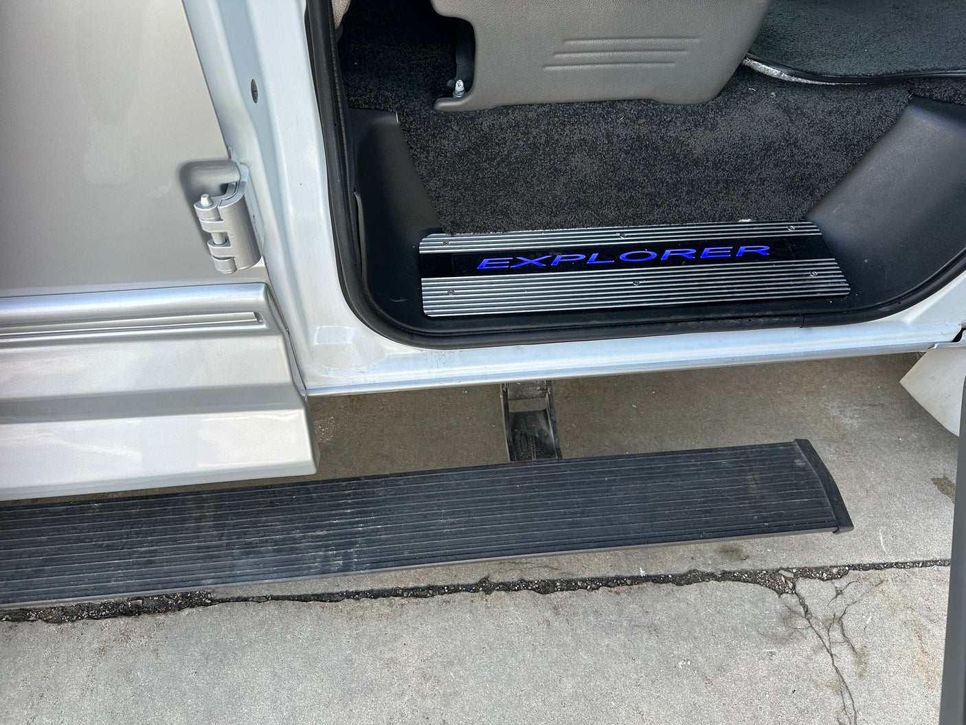 RV rental side entry featuring an illuminated 'EXPLORER' door sill and a sturdy running board for easy access.