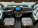 Inside a Ford Transit rv rental, showing the spacious driver's area, dashboard, and infotainment system.