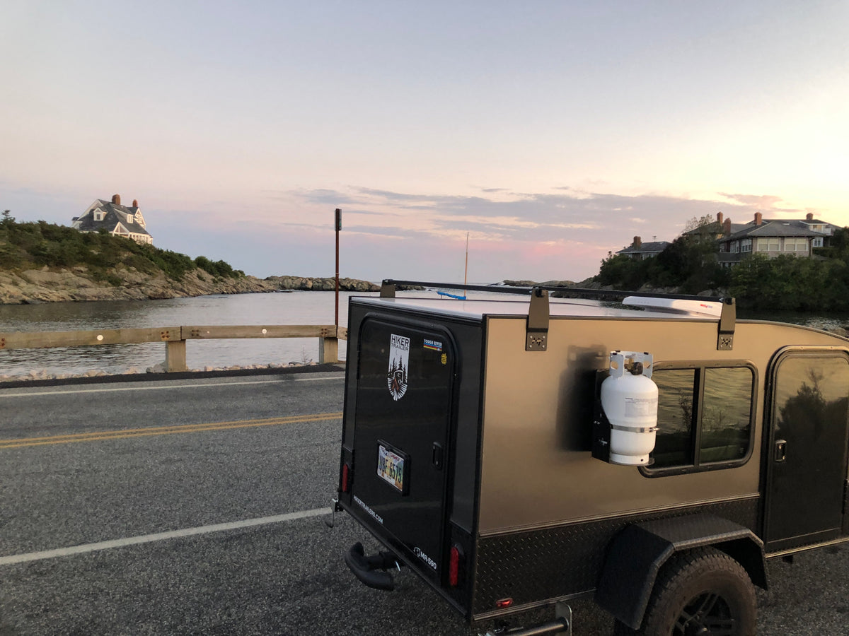RV rental teardrop camper parked on a coastal road overlooking water and houses. Ideal for scenic adventures by the sea. — photo 4
