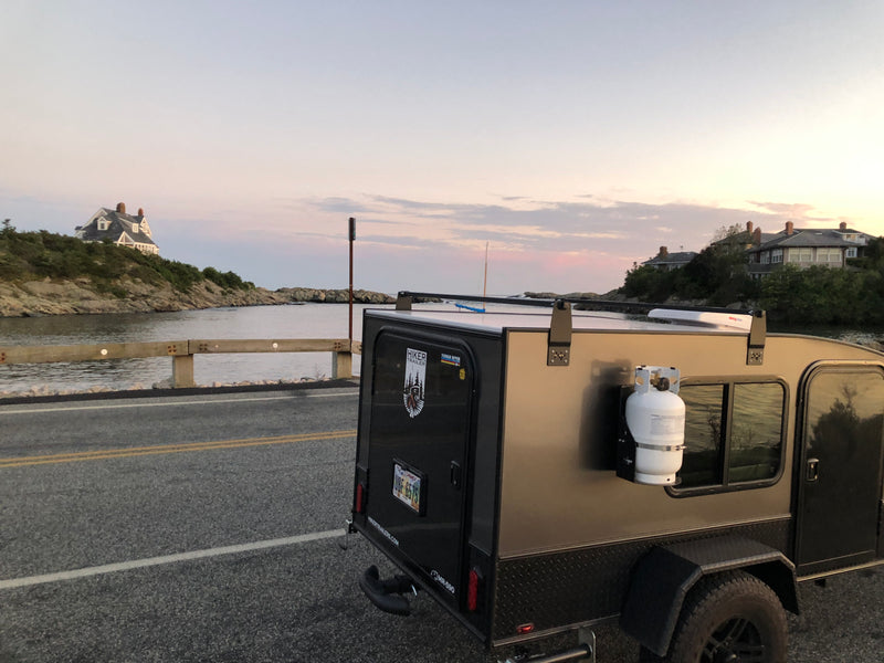 RV rental teardrop camper parked on a coastal road overlooking water and houses. Ideal for scenic adventures by the sea. — photo 4