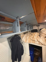 RV rental interior: A comfortable bed, open overhead cabinets with gas struts, and storage below. Ideal for travel.