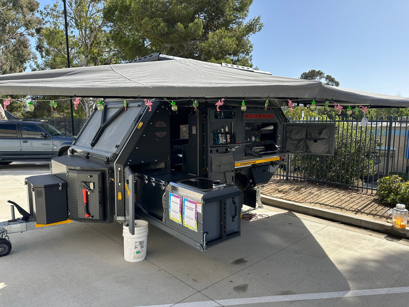 Rugged Conqueror off-road camper trailer, ideal for an adventure RV rental. Features an outdoor kitchen, awning, and festive lights. — photo 6
