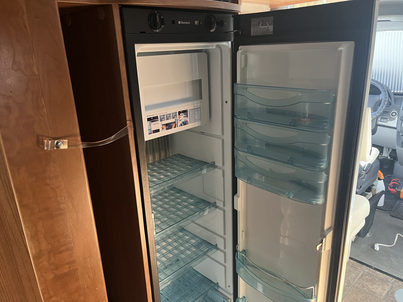 Inside an RV rental: a clean, empty Dometic refrigerator with open doors, showing shelves and bins. — photo 16