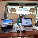 Mobile office setup in an RV rental. Two laptops, water bottle, and accessories on table for remote work and digital nomad lifestyle.
