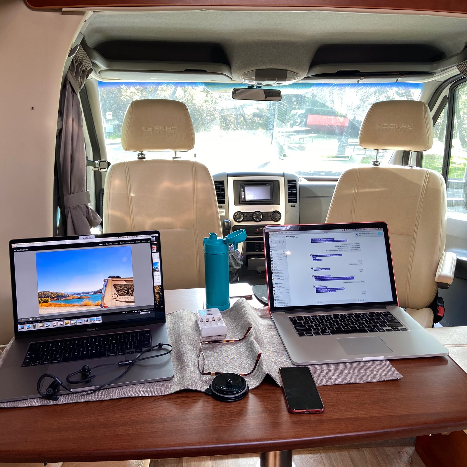 Mobile office setup in an RV rental. Two laptops, water bottle, and accessories on table for remote work and digital nomad lifestyle.
