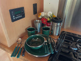 RV rental's equipped kitchen: green enamelware, Stanley mug, stove, and control panel for comfortable camping.