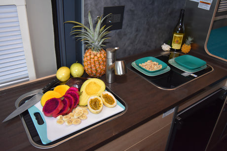 Fresh tropical fruits like pineapple, mango, and nuts in this compact RV rental kitchen, ideal for healthy travel meals.