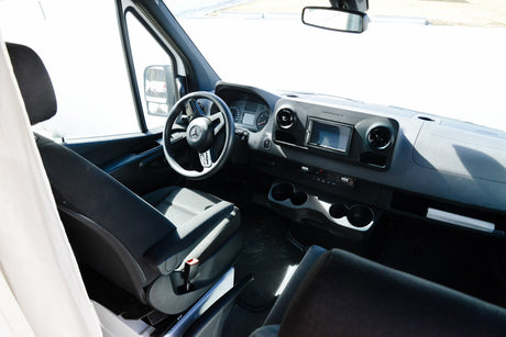 Front cabin view of an RV rental Mercedes Sprinter van, featuring the driver's seat, steering wheel, and dashboard.