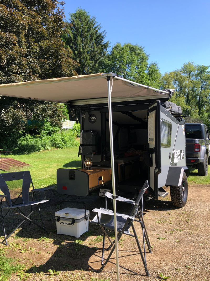 This compact Tiger Moth off-road camper, ideal for RV rental adventures, features an awning, chairs, and kitchen setup. — photo 6