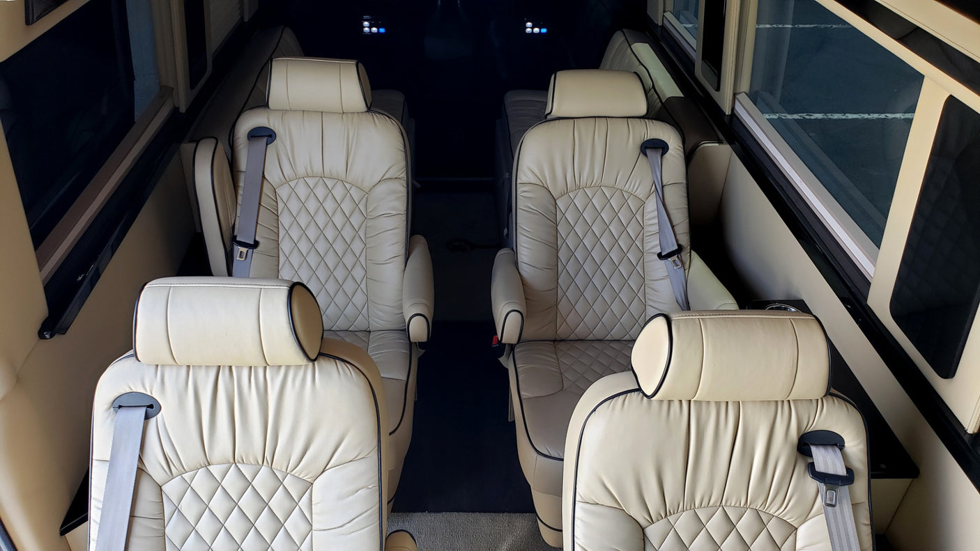 Luxury RV rental interior featuring plush cream leather captain seats with diamond stitching and seatbelts.