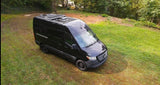 Overhead view of a sleek black Mercedes-Benz Sprinter camper van, perfect for your next rv rental, parked on grass.