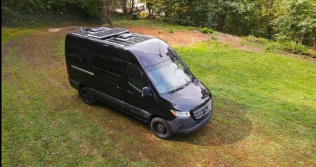 Overhead view of a sleek black Mercedes-Benz Sprinter camper van, perfect for your next rv rental, parked on grass.