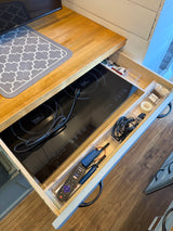 This rv rental kitchen features a cleverly organized drawer with a True Induction cooktop, TV remote, and charging cables.