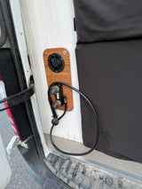 RV rental: Rear area features an outdoor shower station with controls, hose, and water fill on a wood panel.