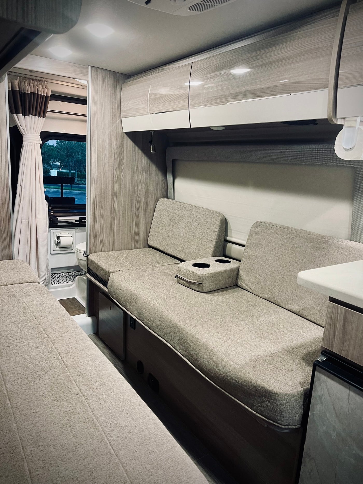  near a picnic table.|Modern RV rental interior: cozy facing benches with pillows — photo 4