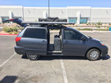 Gray minivan with open side door, trunk, and rooftop camping awning, hinting at a versatile rv rental option for adventures.