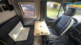 RV rental interior shows a camper van's compact living space with a bench seat, folding table, and swivel driver's seat.