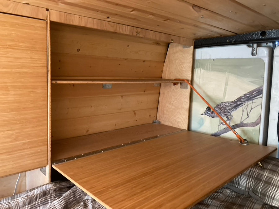 See this RV rental's custom wood interior with a handy fold-down table, shelving, and a detailed roadrunner mural.