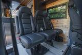 Black leather passenger seats inside a comfortable RV rental. Features a fridge & wood interior for travel.