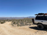 Off-road SUV in a vast desert landscape with mountains. Perfect for adventure travel or an RV rental getaway.