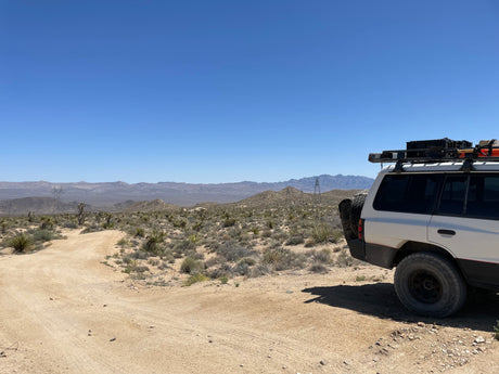 Off-road SUV in a vast desert landscape with mountains. Perfect for adventure travel or an RV rental getaway.
