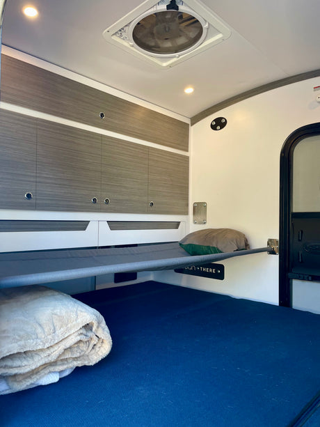 RV rental interior featuring bunk beds, storage cabinets, and a lower bed, ideal for compact adventure travel.