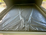 RV rental: Elevated sleeping area with a new mattress still covered in crinkled protective plastic.