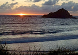 Sunset over a tranquil ocean with a silhouetted island. Plan your next RV rental escape!