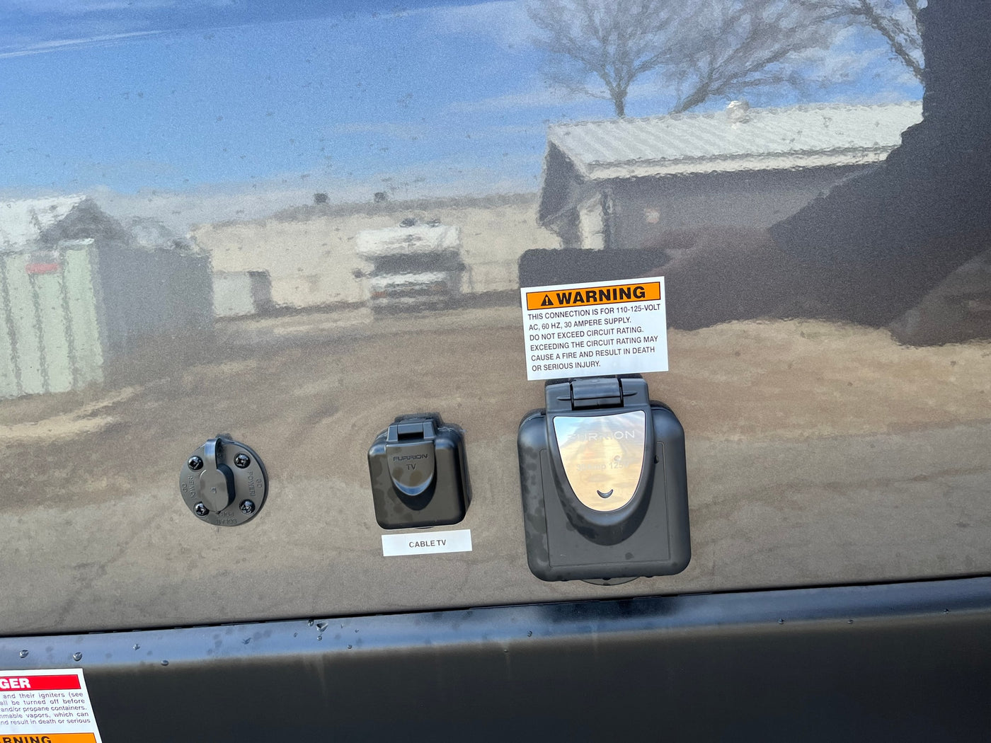 RV rental side panel with solar, cable TV, and 30-amp power connections. Clear warning labels visible. — photo 7