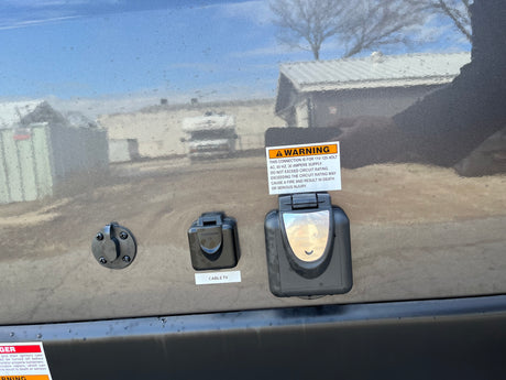 RV rental side panel with solar, cable TV, and 30-amp power connections. Clear warning labels visible.